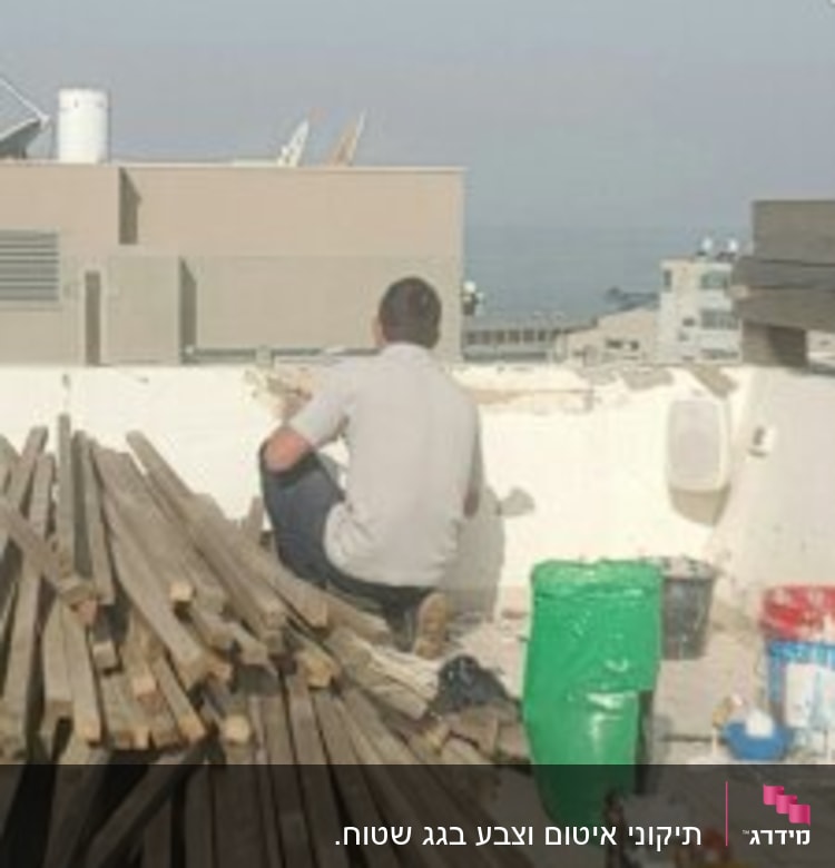 אדם עובד על איטום קיר עם דלי ירוק וכלים